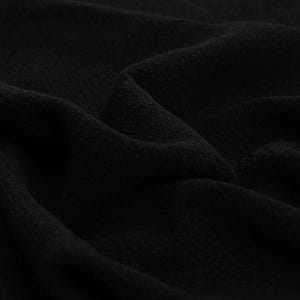 May include: A solid black fabric with a soft, matte texture. The material is draped in deep, flowing folds that create subtle shadows and highlights across the surface, emphasizing the dense, uniform color and the tactile quality of the textile.