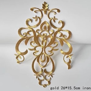May include: Gold iron-on applique with a decorative, ornate design. The applique is 26 cm by 15.5 cm.