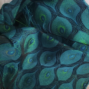 May include: Teal fabric with a peacock feather pattern. The fabric has a subtle shimmer and is woven with a fine thread.