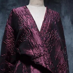 May include: A burgundy silk kimono with a black floral pattern. The kimono has a V-neck and long sleeves.