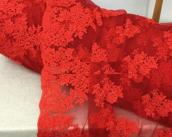 May include: Red floral lace fabric with a delicate pattern. The lace is sheer and has a soft, flowing texture.