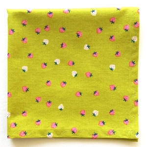 May include: Square, lime green fabric with a repeating pattern of pink and white strawberries. The fabric has a scalloped edge. The strawberries have green stems and are scattered across the surface.