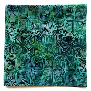 May include: Square fabric with a repeating pattern of concentric squares and circles in shades of teal, green, and blue. The fabric has a batik-style design with a textured appearance.