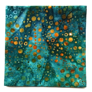 May include: Square fabric with a teal and turquoise background, featuring a pattern of orange and gold circles of varying sizes. The fabric has a batik-like appearance, with a stitched border.