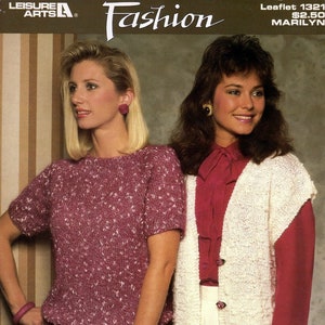 May include: Two women wearing knitted sweaters. The woman on the left is wearing a pink sweater with white flecks. The woman on the right is wearing a white sweater with a red blouse underneath. The text "nomotta MARILYN" is featured on the image.