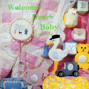 May include: A collection of cross-stitch patterns for baby items, including a rocking horse, a teddy bear, a stork, and a pillow. The patterns are from the Flutterbox Designs book, "Welcome Dear Baby".