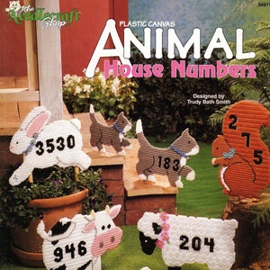 May include: Plastic canvas pattern for five animal house numbers. The animals include a rabbit, cat, squirrel, cow, and sheep. The numbers are 3530, 183, 275, 946, and 204. The pattern is designed by Trudy Bath Smith.