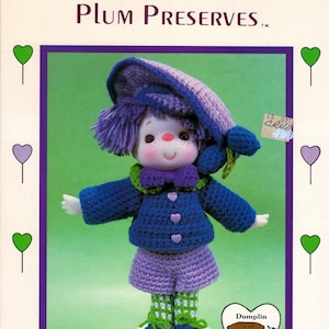 May include: Crochet doll pattern for a purple and blue doll wearing a green hat and a purple dress. The pattern is called "Plum Preserves" and is brought to you directly from "Lollipop Lane".