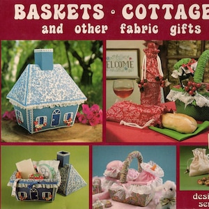 May include: A vintage craft book cover featuring a collection of fabric gift ideas. The cover shows four different projects: a blue and white cottage-shaped box, a red and white wine bottle holder, a green and white basket, and a beige fabric bag. The title of the book is "BASKETS COTTAGES and other fabric gifts".