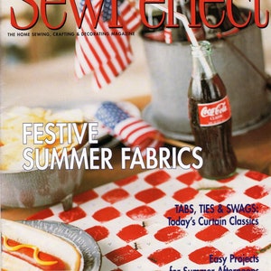 May include: A magazine cover featuring a red and white checkered tablecloth with a hot dog on a plate, a bottle of Coca-Cola, and a red, white, and blue American flag. The magazine is titled "Sew Perfect" and the cover text reads "Festive Summer Fabrics".