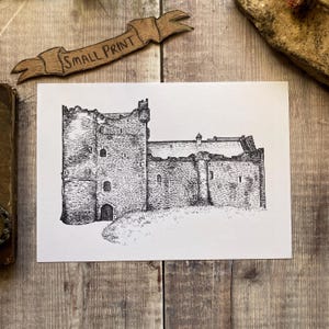 May include: A detailed pen and ink drawing of a stone castle, featuring a tall tower and multiple windows. A banner above the drawing reads "SMALL PRINT". The artwork is on white paper.