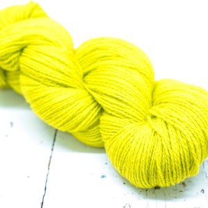 Pode incluir: Um novelo de fio amarelo brilhante, perfeito para tricotar ou fazer croch&ecirc;.