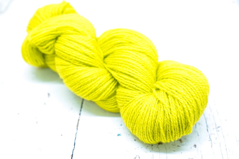 Pode incluir: Um novelo de fio amarelo brilhante, perfeito para tricotar ou fazer croch&ecirc;.