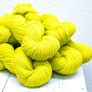 Pode incluir: Um monte de novelos de l&atilde; amarelo brilhante, perfeitos para projetos de tric&ocirc; ou croch&ecirc;.