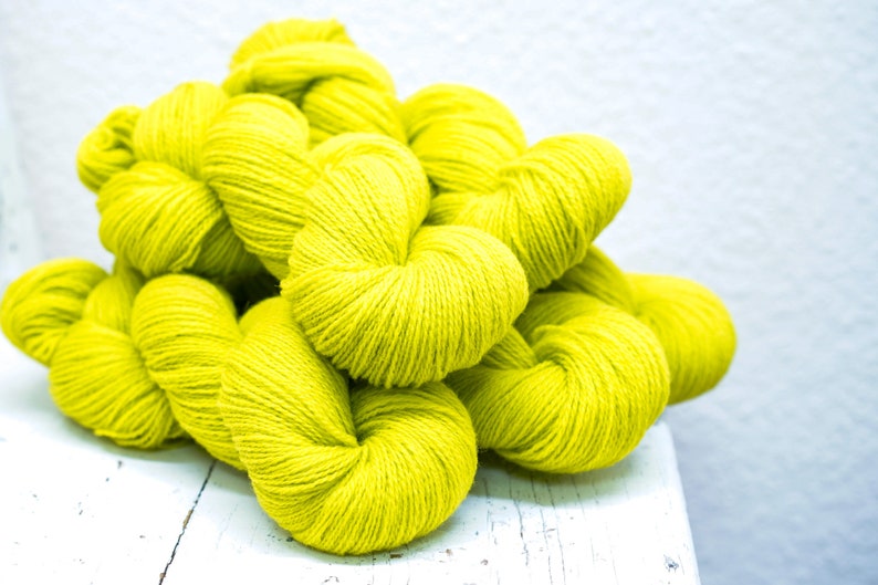 Pode incluir: Um monte de novelos de l&atilde; amarelo brilhante, perfeitos para projetos de tric&ocirc; ou croch&ecirc;.