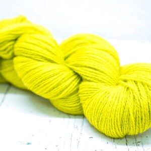 Pode incluir: Uma bola de fio amarelo brilhante, perfeita para projetos de tric&ocirc; ou croch&ecirc;.