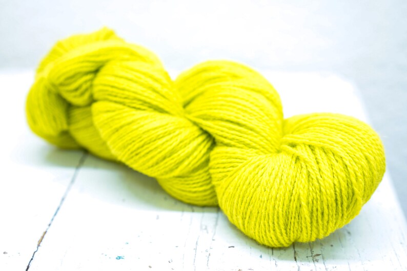 Pode incluir: Uma bola de fio amarelo brilhante, perfeita para projetos de tric&ocirc; ou croch&ecirc;.
