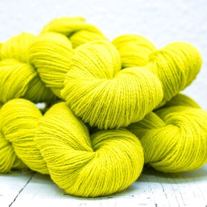 Pode incluir: Um monte de novelos de l&atilde; amarelo brilhante. A l&atilde; &eacute; macia e fofa, perfeita para tricotar ou fazer croch&ecirc;.