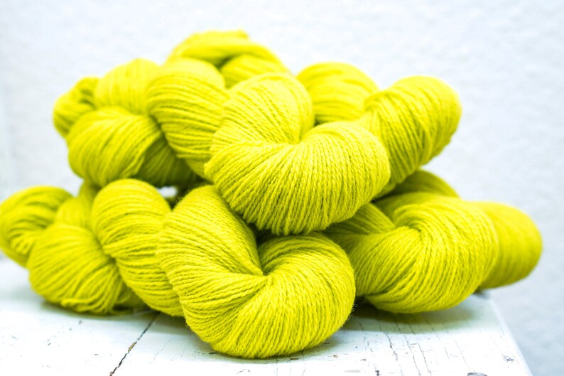 Pode incluir: Um monte de novelos de l&atilde; amarelo brilhante. A l&atilde; &eacute; macia e fofa, perfeita para tricotar ou fazer croch&ecirc;.