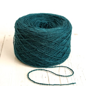 May include: A ball of teal blue yarn, wound into a skein, with a length of yarn extending from the centre.
