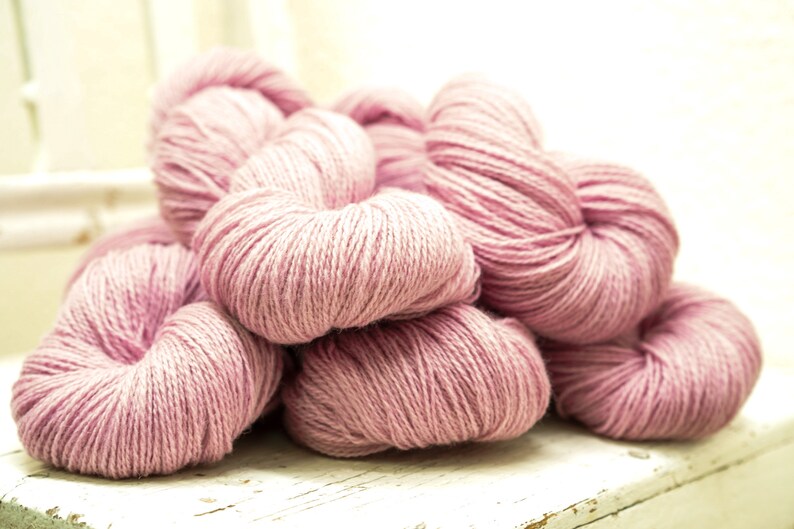 May include: A pile of soft, pink yarn skeins, perfect for knitting or crocheting projects.