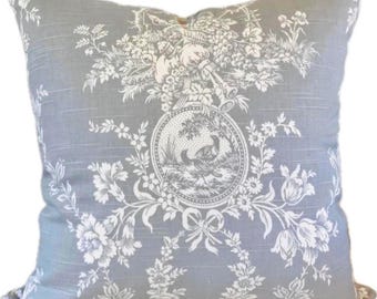 May include: A square throw pillow featuring a light gray fabric base with a white toile pattern. The design includes a central circular medallion depicting two birds in a landscape, surrounded by floral motifs, ribbons, and foliage.