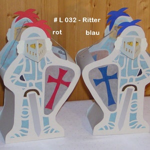 Könnte beinhalten: Zwei Ritterfiguren aus Papier, eine mit rotem Kreuz auf dem Schild und roter Feder, die andere mit blauem Kreuz und blauer Feder. Jeder Ritter hat ein Silberschwert und einen Helm mit gelbem Visier. Der Text lautet "# L 032 - Ritter rot blau".