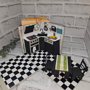 Könnte beinhalten: Eine handgefertigte Pop-up-Küchenszene mit einem schwarz-weiß karierten Boden, einer schwarzen Küchenzeile und einem kleinen Tisch mit Stühlen. Die Küche verfügt über einen Herd, eine Spüle und Geräte.