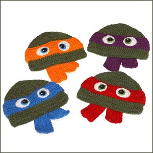 Puede incluir: Cuatro gorros de ganchillo en verde, naranja, morado y rojo, cada uno con una máscara de color diferente y ojos blancos. Los gorros están diseñados para parecerse a las Tortugas Ninja.