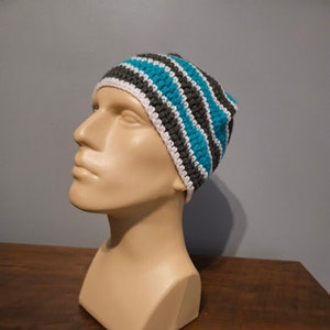 May include: A striped crocheted beanie hat in gray, white, and teal.