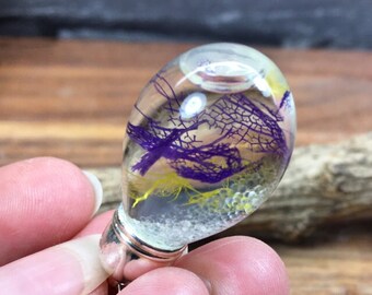 Glass bead filled with transparent oil with pearls and colorful veil leaves