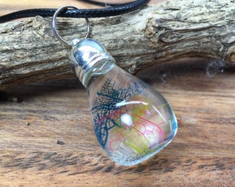 Glass bead filled with transparent oil with pearls and colorful veil leaves