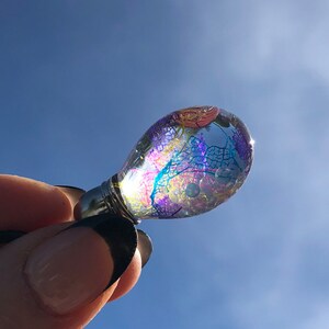 Glass bead filled with transparent oil with pearls and colorful veil leaves