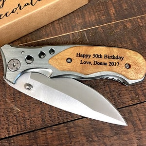 May include: A silver pocket knife with a wooden handle engraved with the text "Happy 50th Birthday Love, Donna 2017".