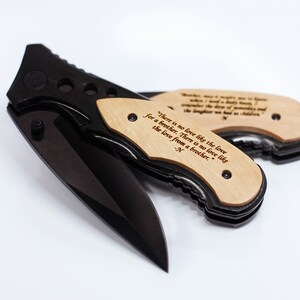 May include: A black pocket knife with a wooden handle engraved with the quote "There is no love like the love for a brother. There is no love like the love from a brother." - N