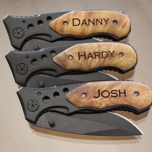 May include: Three personalized pocket knives with wooden handles. The handles are engraved with the names "DANNY", "HARDY", and "JOSH".