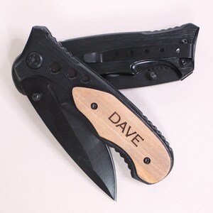 May include: A black pocket knife with a wooden handle engraved with the name "DAVE".