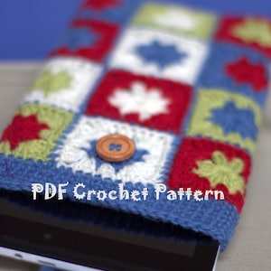 Puede incluir: Una funda para tablet de crochet con un diseño de patchwork colorido en rojo, azul, verde y blanco. La funda tiene un cierre de botón y el texto "PDF Crochet Pattern" es visible.