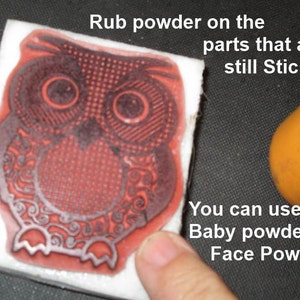 May include: A red owl stamp on a white block, with the text "Rub powder on the parts that are still Sticky... You can use Baby powder or Face Powder". An orange container is in the background.