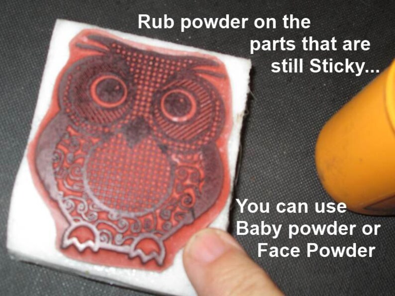 May include: A red owl stamp on a white block, with the text "Rub powder on the parts that are still Sticky... You can use Baby powder or Face Powder". An orange container is in the background.