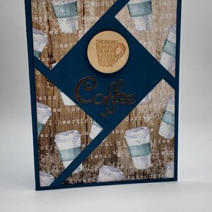 May include: A blue card with a woodgrain background and a coffee cup design. The card has a brown circle with a white coffee cup with polka dots. The text "Coffee" is written in a metallic brown font.