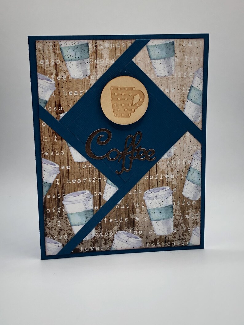 May include: A blue card with a woodgrain background and a coffee cup design. The card has a brown circle with a white coffee cup with polka dots. The text "Coffee" is written in a metallic brown font.