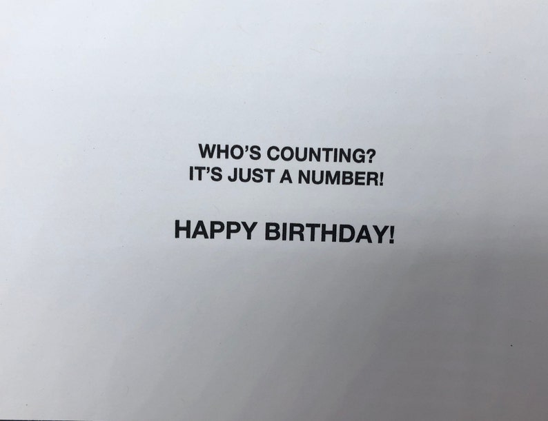 Op de afbeelding: Een witte wenskaart met gecentreerde zwarte tekst op de voorzijde. De tekst luidt: WHO'S COUNTING? IT'S JUST A NUMBER! HAPPY BIRTHDAY! De letters zijn in een strak, vet, schreefloos lettertype, gepresenteerd tegen een effen witte achtergrond.