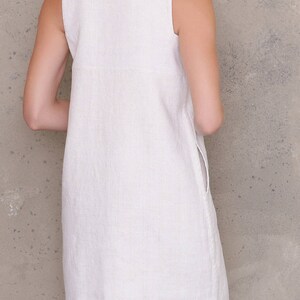 May include: A white linen sleeveless dress with a scoop neck and a straight silhouette.