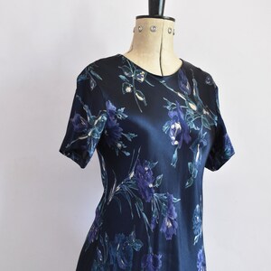 K&ouml;nnte beinhalten: Ein dunkelblaues Satin-Kleid mit einem Blumendruck in Blau- und Gr&uuml;nt&ouml;nen.