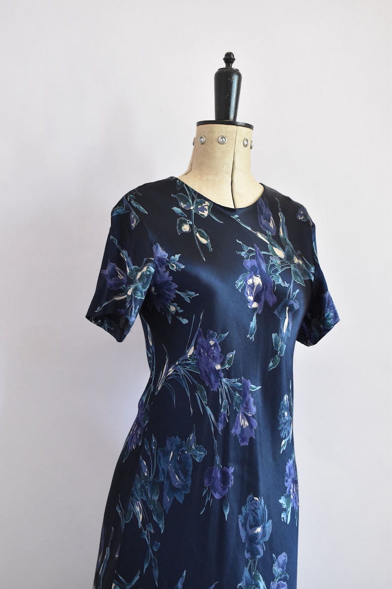 K&ouml;nnte beinhalten: Ein dunkelblaues Satin-Kleid mit einem Blumendruck in Blau- und Gr&uuml;nt&ouml;nen.