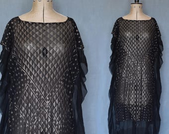 May include: Black evening dress with a square neckline and flowing sleeves. The dress features a diamond pattern with metallic accents. The dress is displayed on a mannequin.
