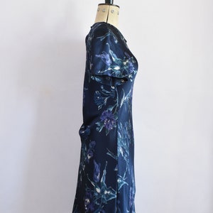 K&ouml;nnte beinhalten: Ein dunkelblaues Kleid mit Blumenmuster. Das Kleid hat kurze &Auml;rmel und eine figurbetonte Silhouette.
