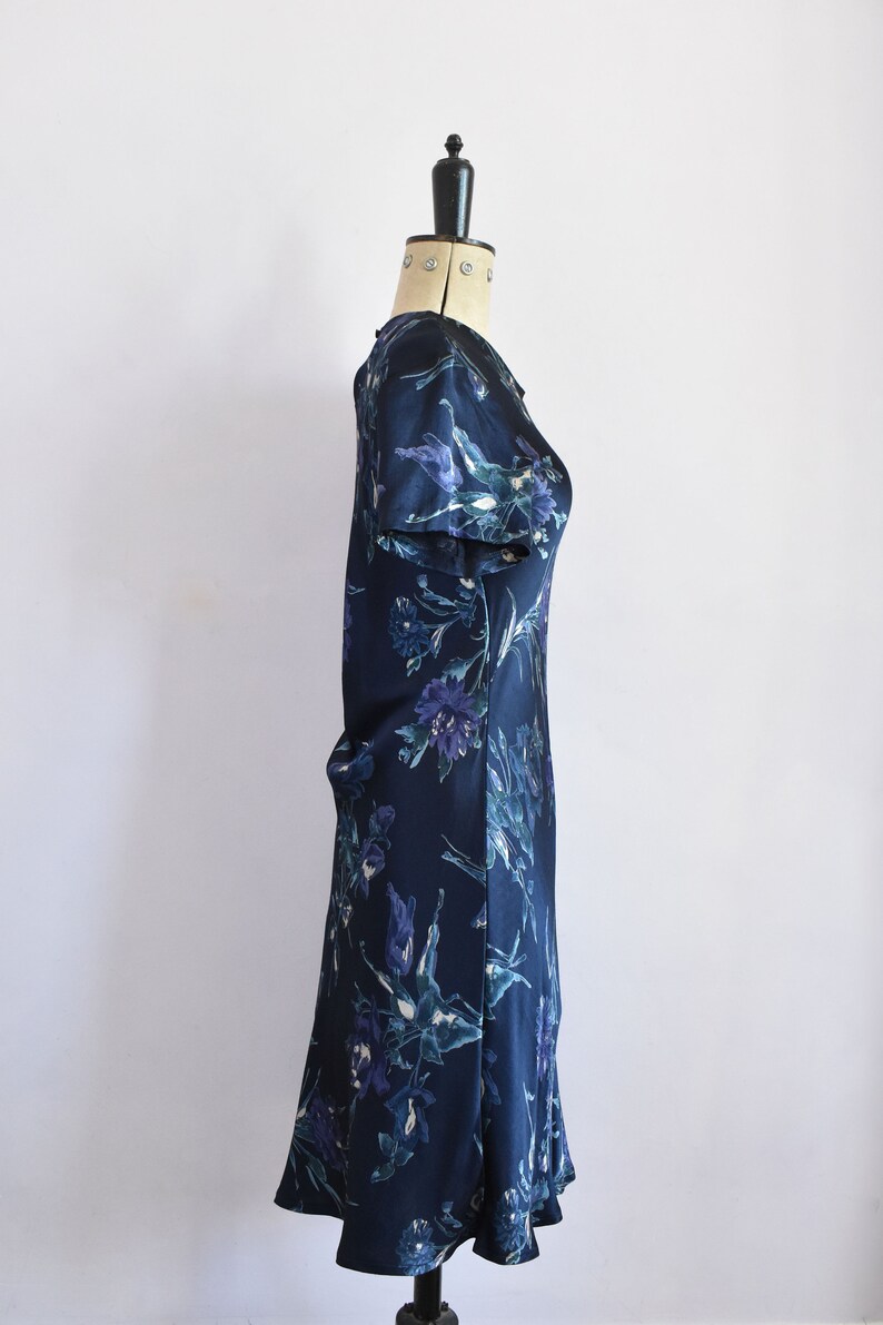 K&ouml;nnte beinhalten: Ein dunkelblaues Kleid mit Blumenmuster. Das Kleid hat kurze &Auml;rmel und eine figurbetonte Silhouette.