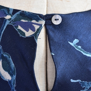 K&ouml;nnte beinhalten: Ein marineblaues Samtkleid mit Blumendruck und einem Schl&uuml;sselschl&uuml;sselloch am R&uuml;cken. Das Kleid hat einen einzigen Knopfverschluss am Nacken.